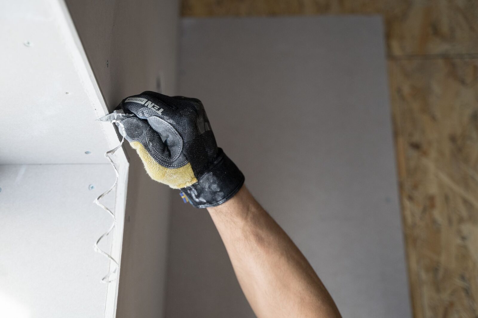 Gloved hand finishing a drywall repair