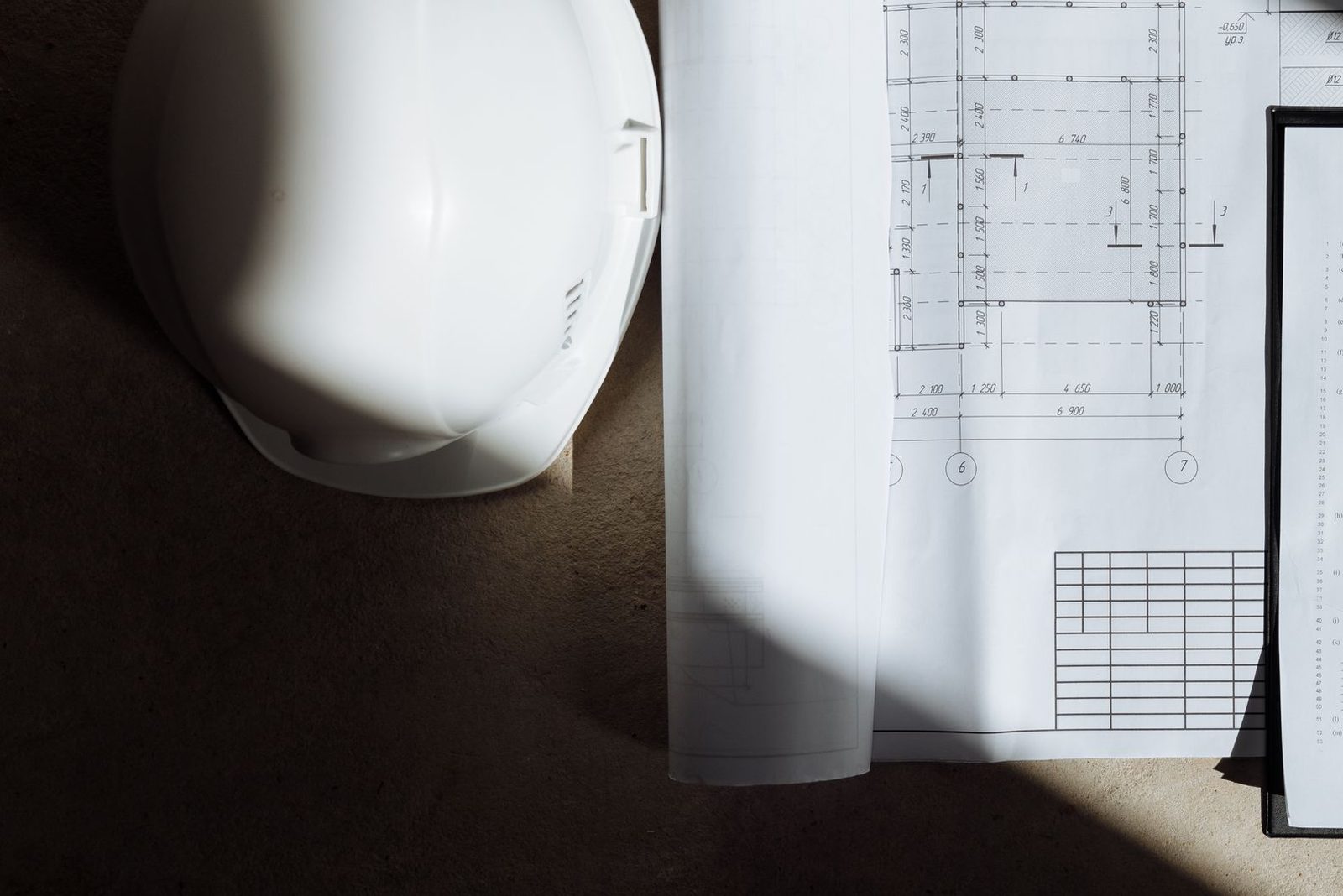 Commercial construction drawings and a hard hat on a job-site floor